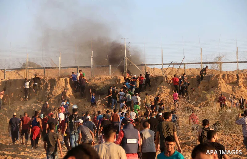 Palestinian protesters gather during clashes with Israeli troops in tents protest where Palestinians demand the right to return to their homeland at the Israel-Gaza border, in Al-Bureij in the center of Gaza Strip on Aug...
