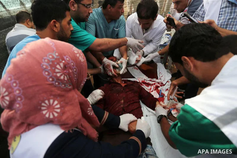 Palestinian medics help a wounded Palestinian protester after he was shot by Israeli troops during clashesin tents protest where Palestinian demand the right to return to their homeland at the Israel-Gaza border, in Khan...