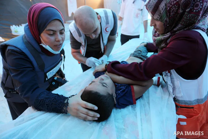 Palestinian medics help a wounded Palestinian protester after he was shot by Israeli troops during clashes in tents protest where Palestinians demand the right to return to their homeland at the Israel-Gaza border, in Kh...