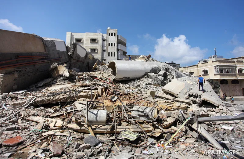 Palestinian men stand on the rubble of Said al-Mishal Cultural Center which was destroyed by an Israeli air strike in Gaza city on Aug. 11, 2018. Photo by Mahmoud Ajour