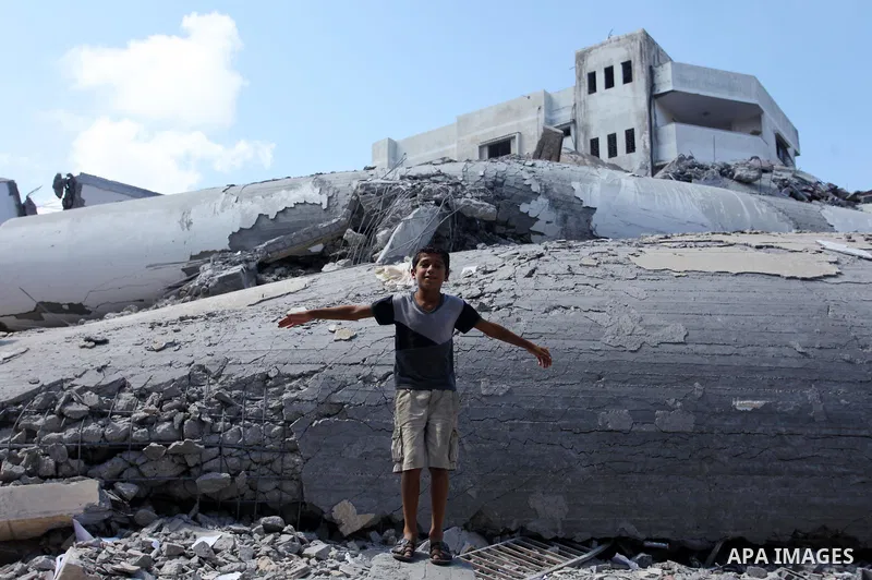 A Palestinian boy stands on the rubble of Said al-Mishal Cultural Center which was destroyed by an Israeli air strike in Gaza city on Aug. 11, 2018. Photo by Mahmoud Ajour