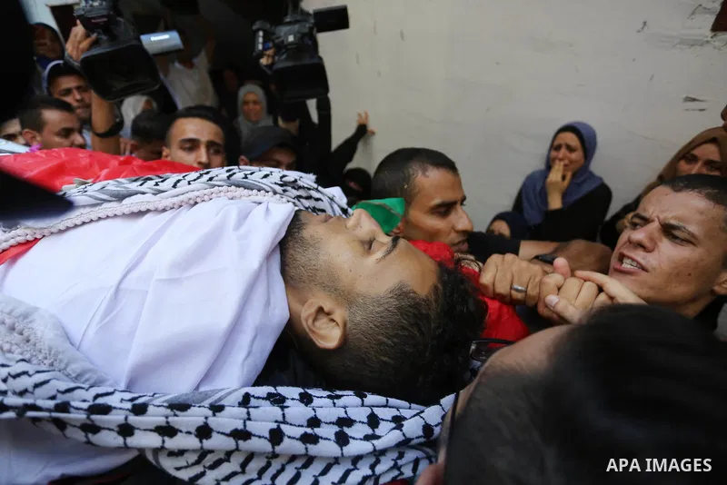 Mourners carry the body of Palestinian volunteer medic Abdullah Al-Kotati, who was killed the day before by Israeli troops while trying to help wounded protesters during clashes where Palestinians demand the right to ret...