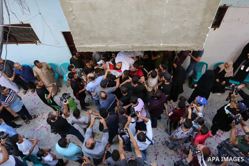 Mourners carry the body of Palestinian volunteer medic Abdullah Al-Kotati, who was killed the day before by Israeli troops while trying to help wounded protesters during clashes where Palestinians demand the right to ret...