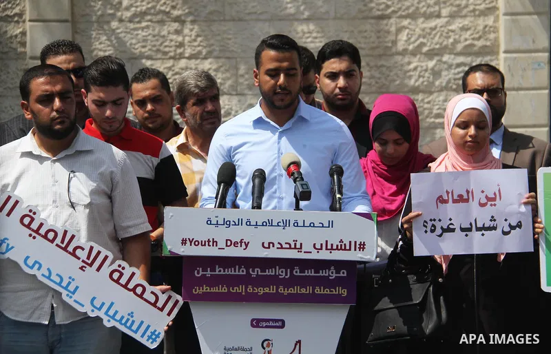 Palestinian youths hold banners during a protest to demand their rights in front of United Nations Development Programme office (UNDP) in Gaza City on August 12, 2018. Photo by Mahmoud Ajour