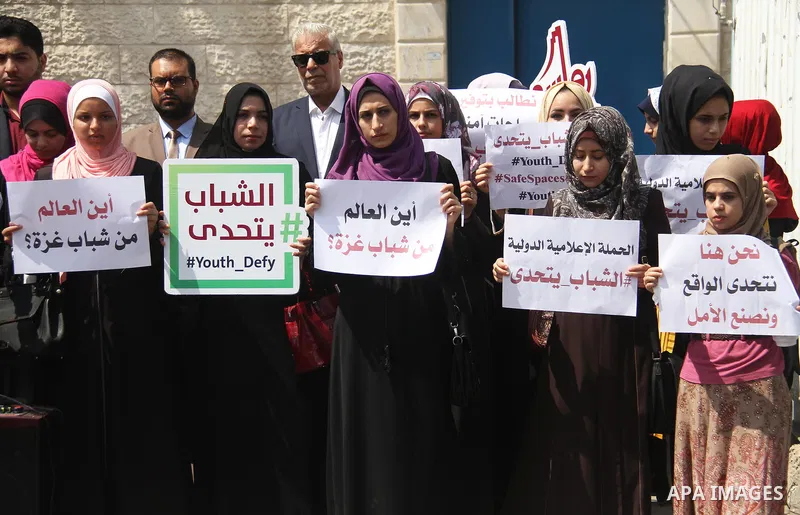 Palestinian youths hold banners during a protest to demand their rights in front of United Nations Development Programme office (UNDP) in Gaza City on August 12, 2018. Photo by Mahmoud Ajour