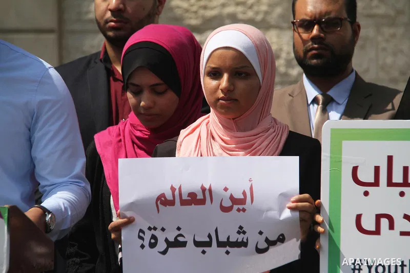 Palestinian youths hold banners during a protest to demand their rights in front of United Nations Development Programme office (UNDP) in Gaza City on August 12, 2018. Photo by Mahmoud Ajour