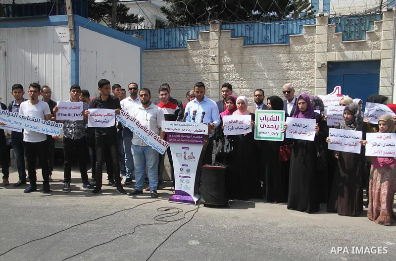 Palestinian youths hold banners during a protest to demand their rights in front of United Nations Development Programme office (UNDP) in Gaza City on August 12, 2018. Photo by Mahmoud Ajour