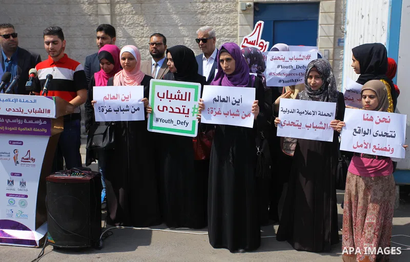 Palestinian youths hold banners during a protest to demand their rights in front of United Nations Development Programme office (UNDP) in Gaza City on August 12, 2018. Photo by Mahmoud Ajour