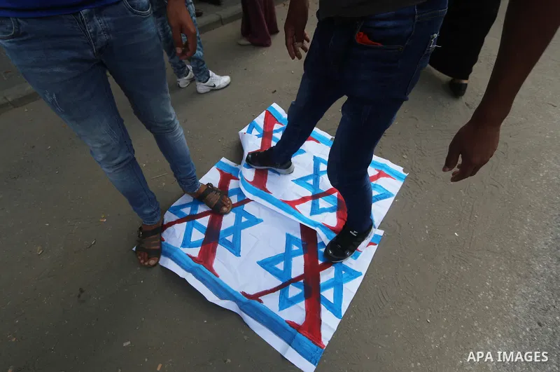 Palestinians burn an Israeli, British and U.S. flags during a protest to show solidarity with Palestinian prisoners held in Israeli jails, in front of Red cross office in Gaza city on August 13, 2018. Photo by Mahmoud Kh...