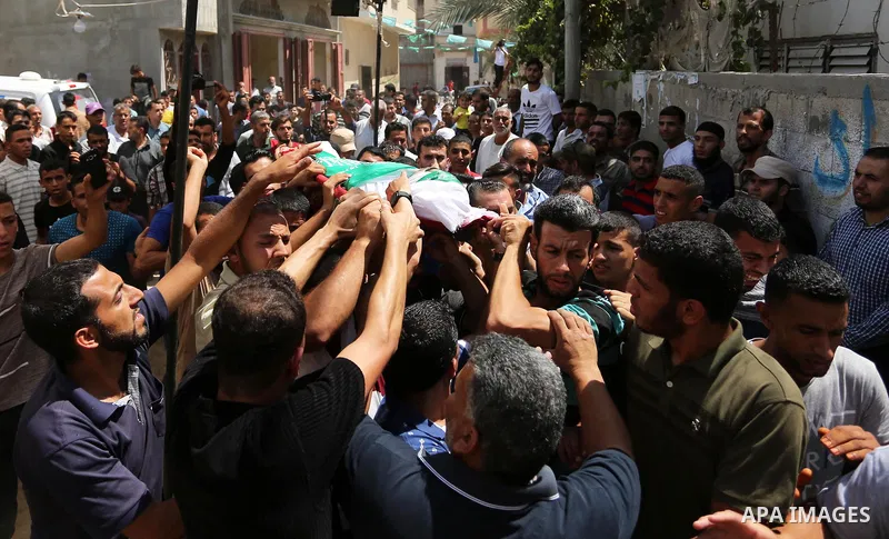 Mourners carry the body of Palestinian Wissam Hijazi, who died of wounds he sustained during clashes with Israeli troops, during his funeral, in Khan Younis in the southern of Gaza Strip on August 13, 2018. Photo by Ashr...