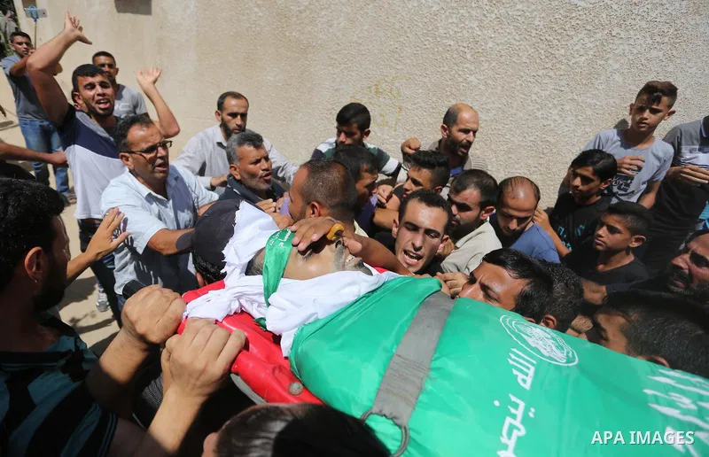 Mourners carry the body of Palestinian Wissam Hijazi, who died of wounds he sustained during clashes with Israeli troops, during his funeral, in Khan Younis in the southern of Gaza Strip on August 13, 2018. Photo by Ashr...