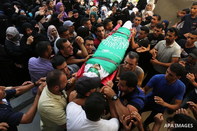 Mourners carry the body of Palestinian Wissam Hijazi, who died of wounds he sustained during clashes with Israeli troops, during his funeral, in Khan Younis in the southern of Gaza Strip on August 13, 2018. Photo by Ashr...