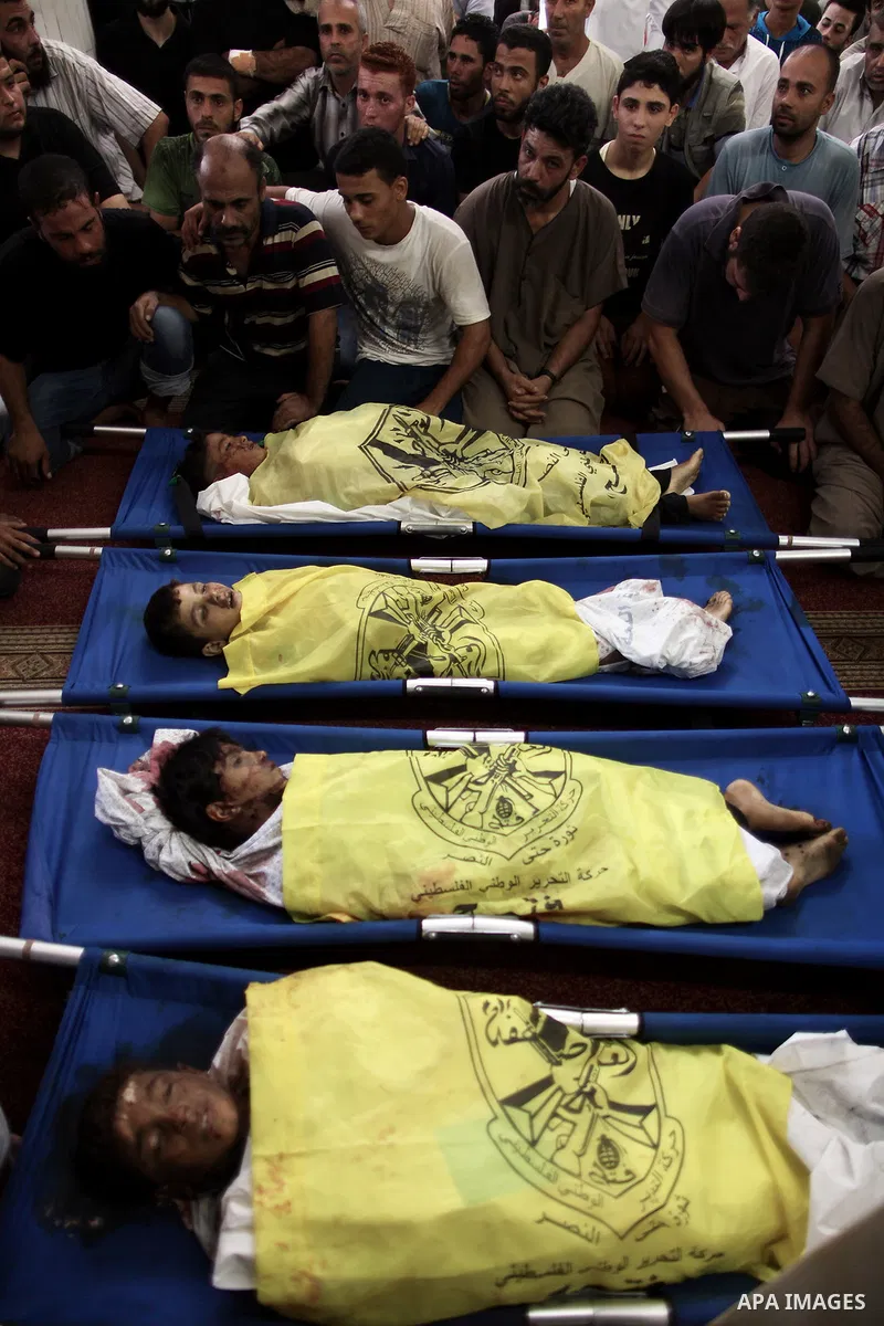 (FILES) This file photo taken on July 16, 2014 shows Palestinians mourn over the body of boys from the Baker family, whom medics said was killed with three other children from the same family by a shell fired by an Israe...