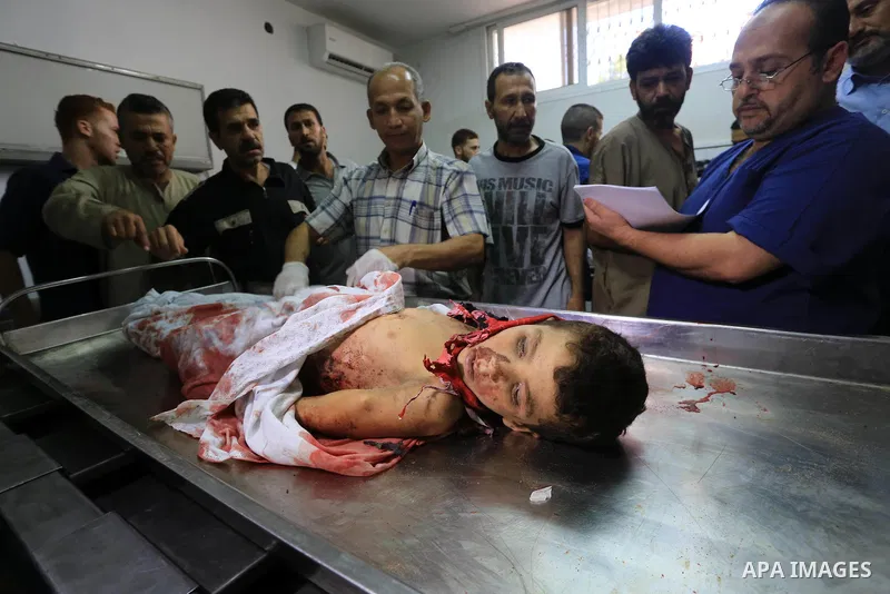 (FILES) This file photo taken on July 16, 2014 shows Palestinians mourn over the body of a boy from the Baker family, whom medics said was killed with other three children from the same family by a shell fired by an Isra...
