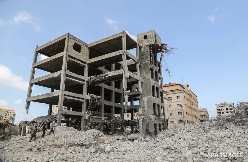 Palestinian workers remove the rubbles from el-katiba building that was damaged in an Israeli airstrike on the Gaza City, on August 14, 2018. Photo by Dawoud Abo Alkas