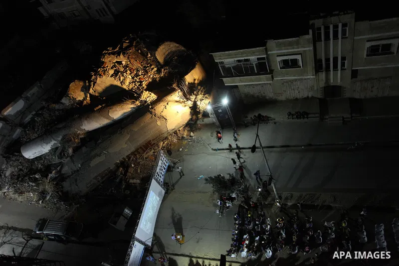 Palestinians watch a movie on large screen next to the rubble of Said al-Mishal Cultural Center which was destroyed by an Israeli air strike in Gaza city on Aug. 14, 2018. Photo by Mahmoud Ajour