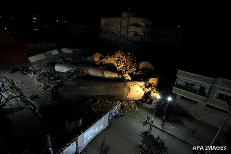 Palestinians watch a movie on large screen next to the rubble of Said al-Mishal Cultural Center which was destroyed by an Israeli air strike in Gaza city on Aug. 14, 2018. Photo by Mahmoud Ajour