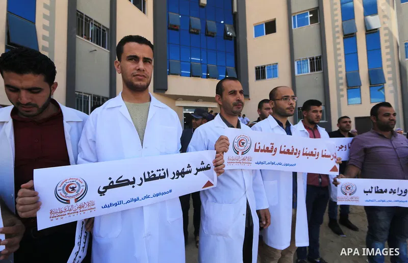 Palestinian Nurses hold banners during a protest to demand their rights, in Gaza city, on August 15, 2018. Photo by Mahmoud Khattab