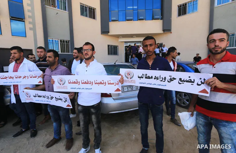 Palestinian Nurses hold banners during a protest to demand their rights, in Gaza city, on August 15, 2018. Photo by Mahmoud Khattab