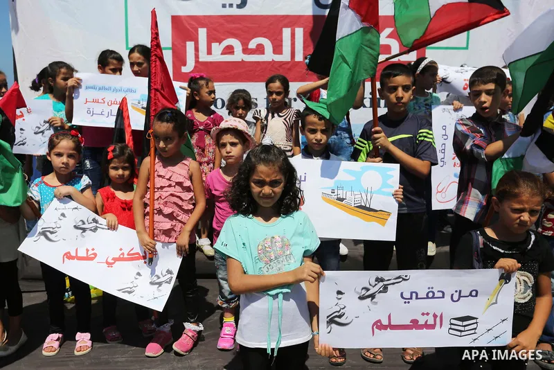 Palestinian children hold banners during a protest to break Israel's blockade on Gaza Strip, at Gaza seaport on August 16, 2018. Photo by Ashraf Amra