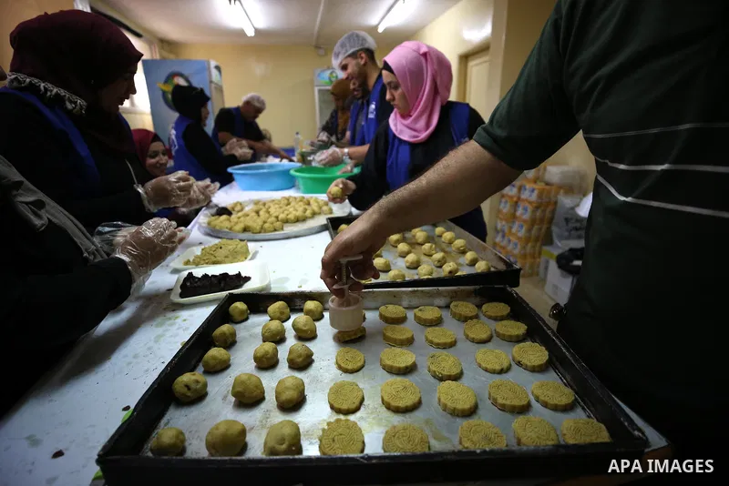 Palestinian volunteers prepare traditional date-filled mini cakes to distribute to poor families ahead of Eid al-Adha in the West Bank city of Nablus on August 15, 2018. Photo by Ayman Ameen