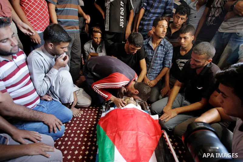Relatives of Palestinian Sadi Moamer, 26, who was killed by Israeli troops the day before during clashes at Israel-Gaza border, mourn over his body during his funeral in Rafah in the southern Gaza Strip on August 18, 201...