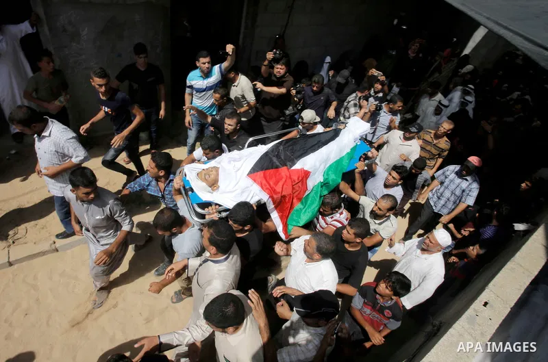 Mourners carry the body of Palestinian Sadi Moamer, 26, who was killed by Israeli troops the day before during clashes at Israel-Gaza border, during his funeral in Rafah in the southern Gaza Strip on August 18, 2018. Pho...