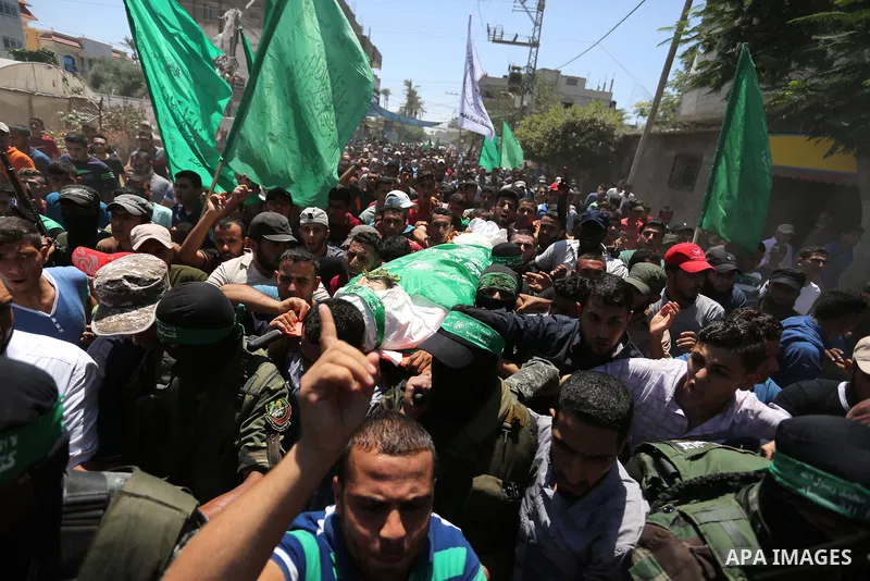 Members of the Islamist movement Hamas' military wing Al-Qassam Brigades carry the body of their comrade Karim Abu Fatayer, 30, who was killed by Israeli troops the day before during clashes at Israel-Gaza border, during...