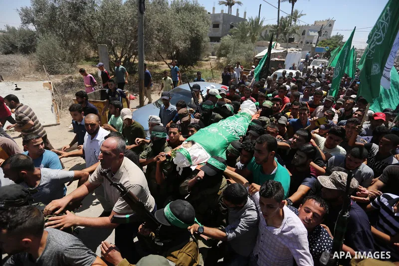 Members of the Islamist movement Hamas' military wing Al-Qassam Brigades carry the body of their comrade Karim Abu Fatayer, 30, who was killed by Israeli troops the day before during clashes at Israel-Gaza border, during...