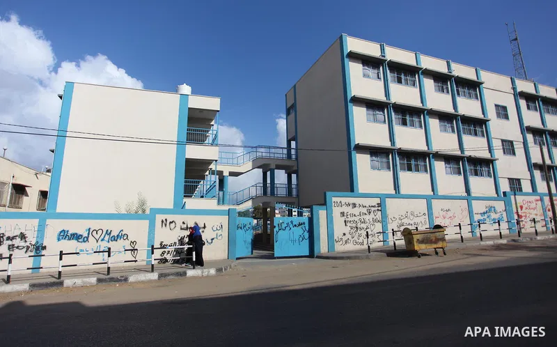 Palestinians walk past the school belonging to the United Nations Relief and Works Agency for Palestinian Refugees (UNRWA) a head of the new school year in Gaza city, on August 27, 2018. Photo by Mahmoud Ajour