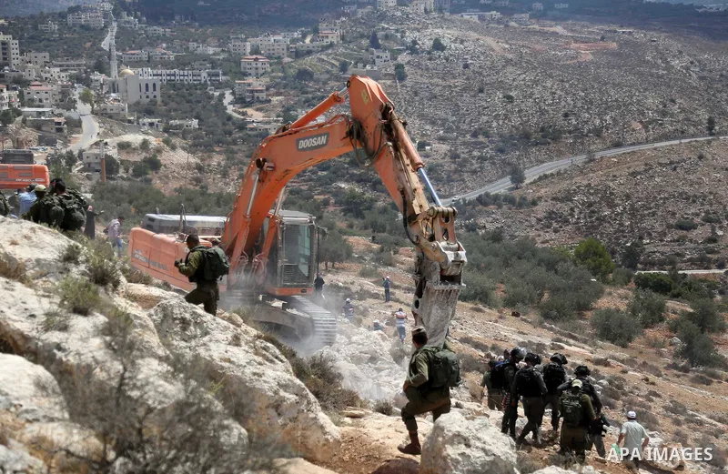 Palestinians gather during a protest where Israeli bulldozer works at Palestinian lands in the village of Ras Karkar, near the West Bank city of Ramallah on August 28, 2018. Photo by Shadi Hatem