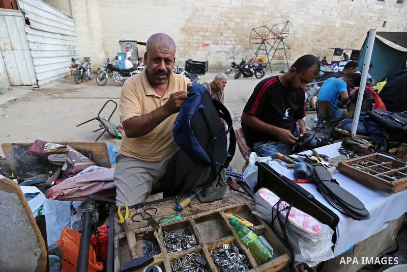 Palestinian tailors re-sewing worn out shoes and bags for students the day before the start of the new school year, at a market, in light of difficult economic and living conditions for Gazans, in Khan Younis in the sout...