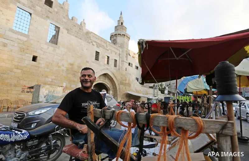 Palestinian tailors re-sewing worn out shoes and bags for students the day before the start of the new school year, at a market, in light of difficult economic and living conditions for Gazans, in Khan Younis in the sout...