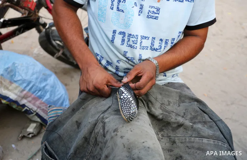 Palestinian tailors re-sewing worn out shoes and bags for students the day before the start of the new school year, at a market, in light of difficult economic and living conditions for Gazans, in Khan Younis in the sout...