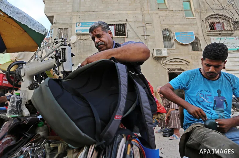 Palestinian tailors re-sewing worn out shoes and bags for students the day before the start of the new school year, at a market, in light of difficult economic and living conditions for Gazans, in Khan Younis in the sout...