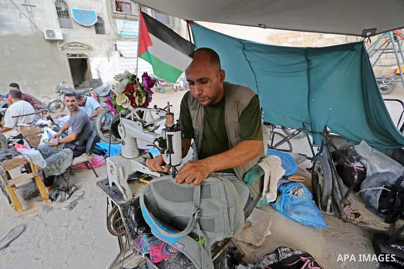 Palestinian tailors re-sewing worn out shoes and bags for students the day before the start of the new school year, at a market, in light of difficult economic and living conditions for Gazans, in Khan Younis in the sout...