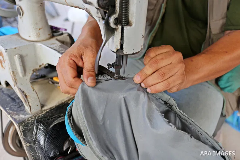 Palestinian tailors re-sewing worn out shoes and bags for students the day before the start of the new school year, at a market, in light of difficult economic and living conditions for Gazans, in Khan Younis in the sout...