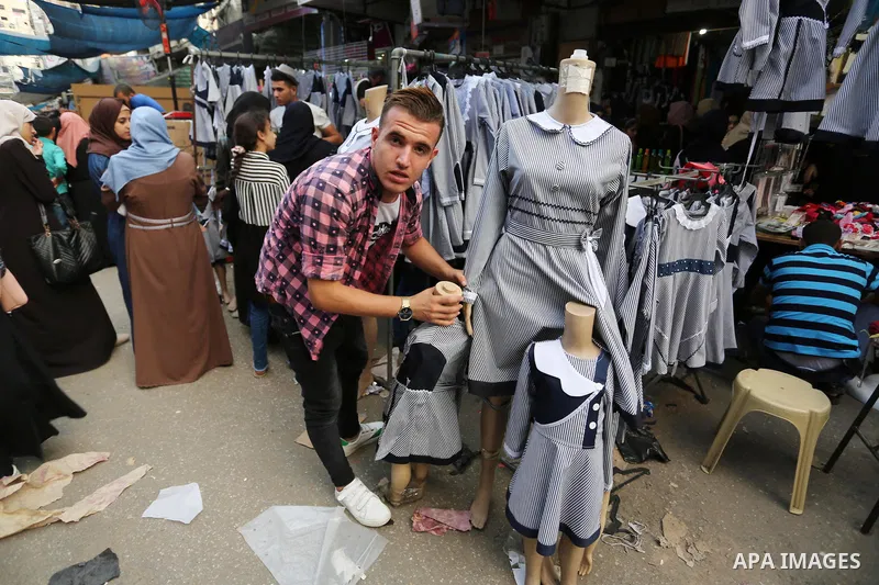 Palestinians shop at a market the day before the start of the new school year, in Khan Younis in the southern of Gaza Strip on August 28, 2018. Photo by Ashraf Amra