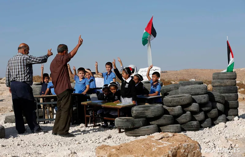 Palestinian schoolchildren attend a class at the site of their school after it was demolished by Israeli security forces who claim it was built on illegal land, on the first day of a new school year in the West Bank vill...