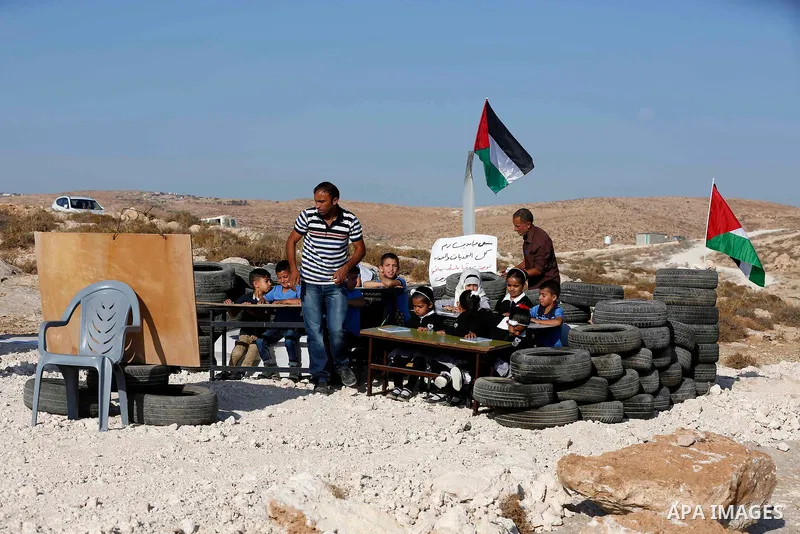 Palestinian schoolchildren attend a class at the site of their school after it was demolished by Israeli security forces who claim it was built on illegal land, on the first day of a new school year in the West Bank vill...