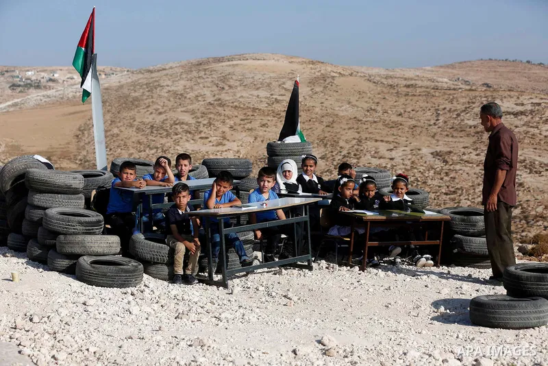 Palestinian schoolchildren attend a class at the site of their school after it was demolished by Israeli security forces who claim it was built on illegal land, on the first day of a new school year in the West Bank vill...