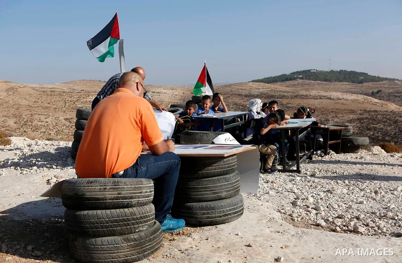 Palestinian schoolchildren attend a class at the site of their school after it was demolished by Israeli security forces who claim it was built on illegal land, on the first day of a new school year in the West Bank vill...