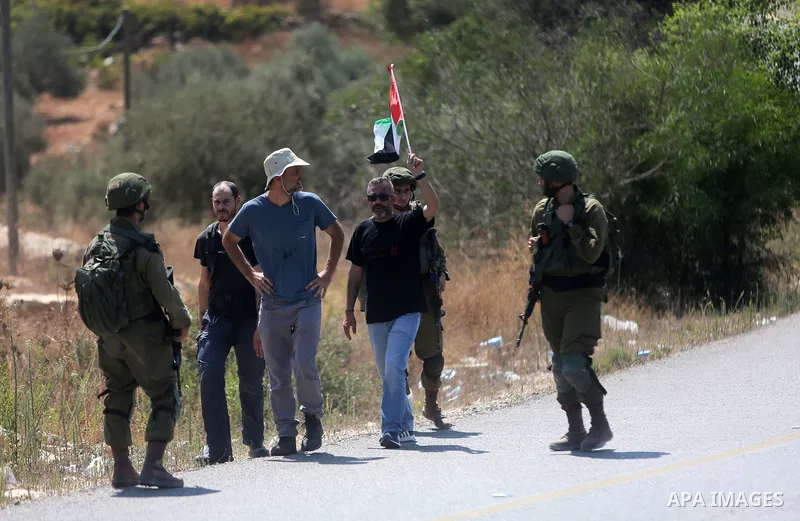 A Palestinian man holds the national flag in front of Israeli border policemen during a protest in the village of Ras Karkar, near the West Bank city of Ramallah on August 29, 2018. Photo by Shadi Hatem