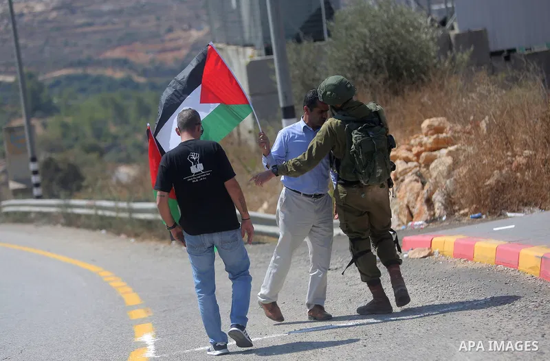 An Israeli border policeman scuffles with a Palestinian man during a protest in the village of Ras Karkar, near the West Bank city of Ramallah on August 29, 2018. Photo by Shadi Hatem