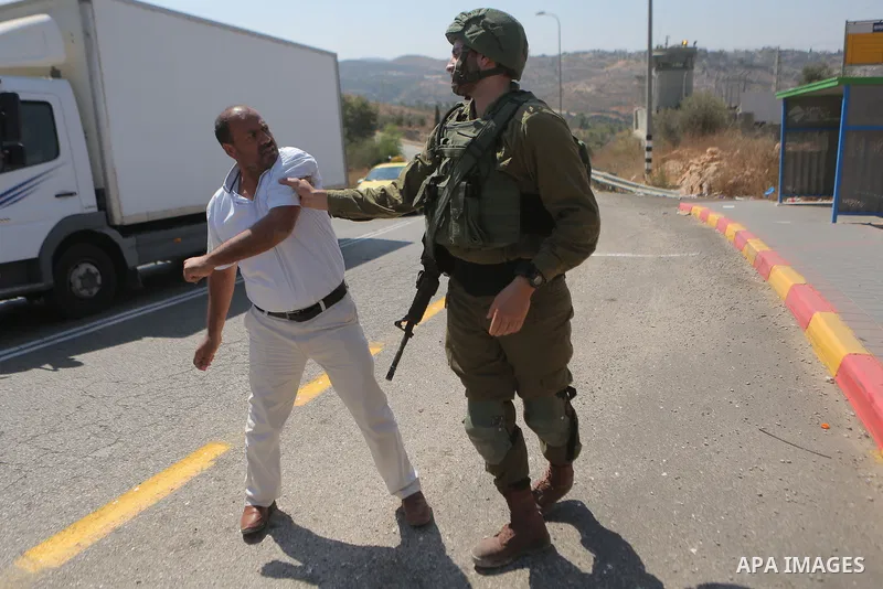 An Israeli border policeman scuffles with a Palestinian man during a protest in the village of Ras Karkar, near the West Bank city of Ramallah on August 29, 2018. Photo by Shadi Hatem