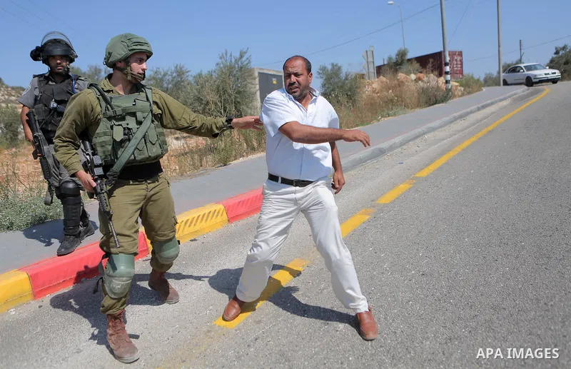 An Israeli border policeman scuffles with a Palestinian man during a protest in the village of Ras Karkar, near the West Bank city of Ramallah on August 29, 2018. Photo by Shadi Hatem