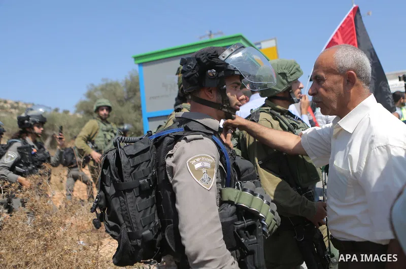 An Israeli border policeman scuffles with a Palestinian man during a protest in the village of Ras Karkar, near the West Bank city of Ramallah on August 29, 2018. Photo by Shadi Hatem