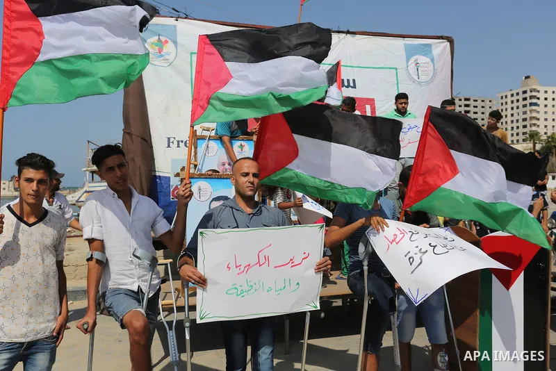 Palestinians hold banners during a protest to break Israel's blockade on Gaza, at Gaza seaport, on August 30, 2018. Photo by Ashraf Amra