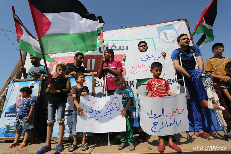 Palestinians hold banners during a protest to break Israel's blockade on Gaza, at Gaza seaport, on August 30, 2018. Photo by Ashraf Amra