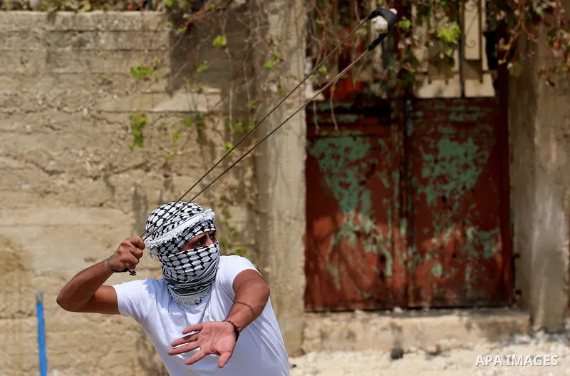 A Palestinian protester uses a slingshot to hurl stones towards Israeli forces during clashes following a weekly demonstration against the expropriation of Palestinian land by Israel in the village of Kfar Qaddum, near t...